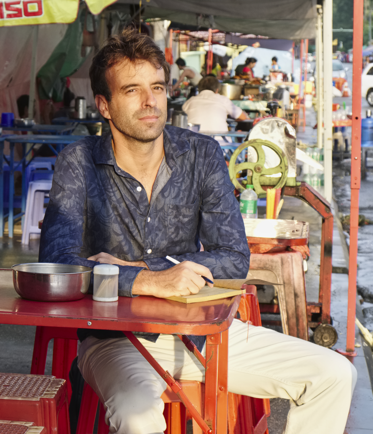 Joan Bastide avec son carnet dans un marché de rue